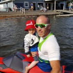 Ryan in his K1 at the dock holding son Logan in his arms